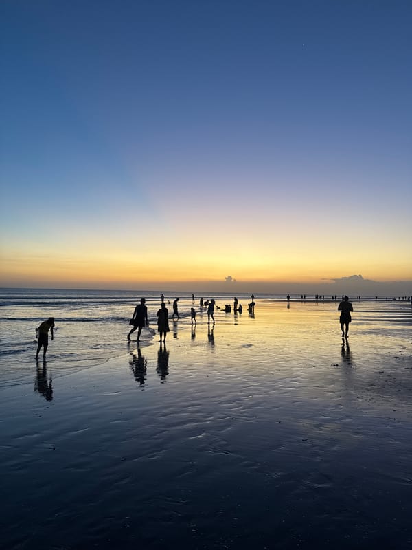 Kuta Beach at golden hour, crowds, music, and fading light