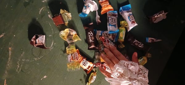 Hand reaches for scattered chocolates on Moscow table