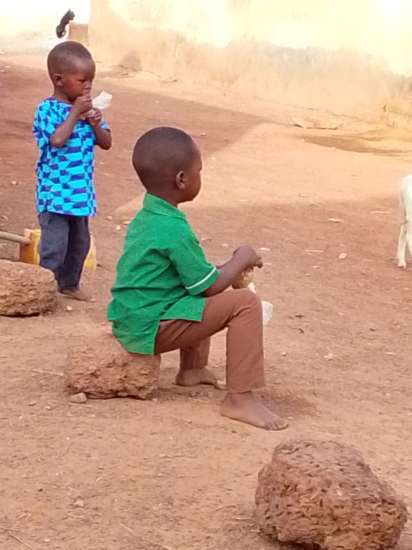 Children play and eat in morning scenes around Tamale