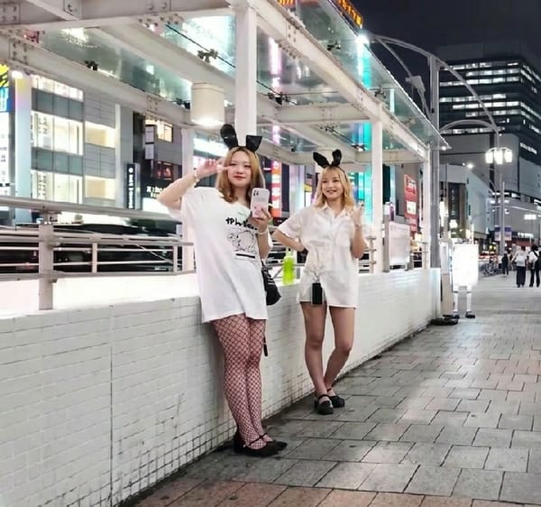 Costumed women pose for photos in Tokyo's Shinjuku district