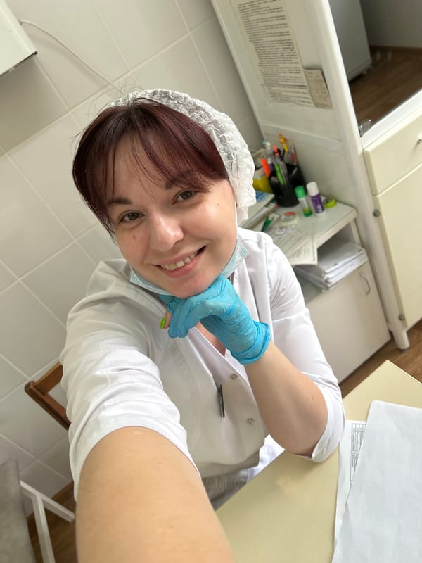 Lab coat and gloves, smiling in a tiled workspace