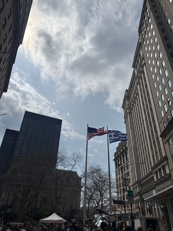 NYC street scene features American and Greek flags