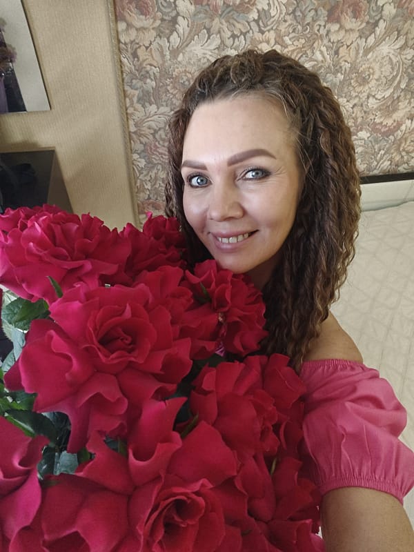 Woman poses with red roses bouquet in interior setting