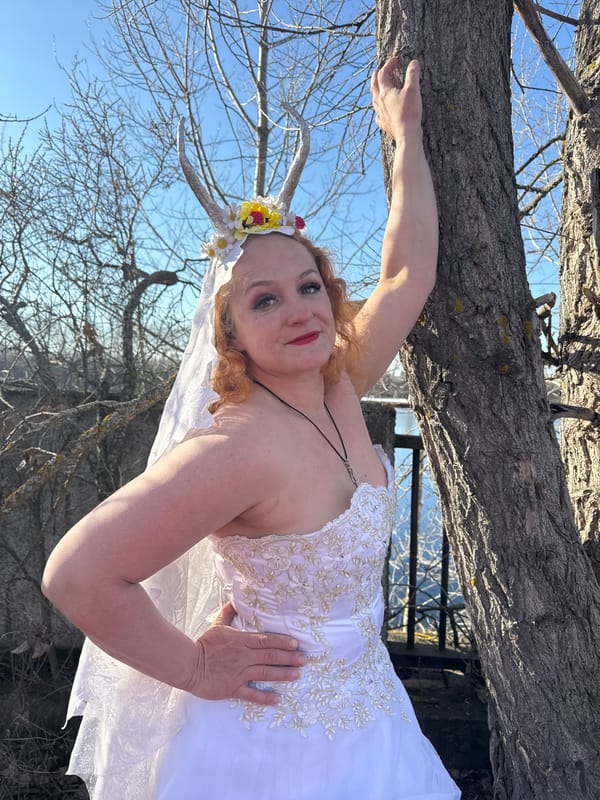 Woman in horned floral crown poses on trees in Russian forest