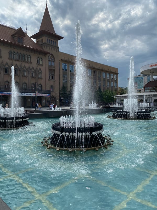 Plaza fountains, riverside lawns, and city streets on a June morning