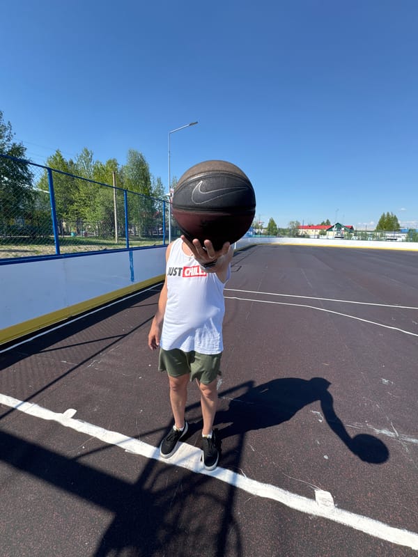 Man plays basketball on sunny morning in Vysokiy, Russia