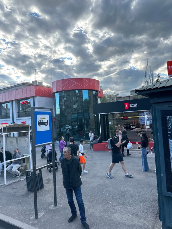 Pedestrians gather at Yerevan bus stop near cafes