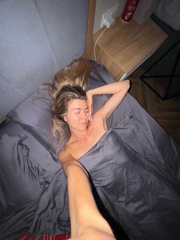 Woman sleeps peacefully in gray-sheeted bed, morning hours