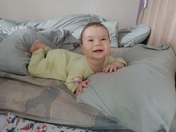 Baby in green onesie photographed smiling in Rusalevka, Russia