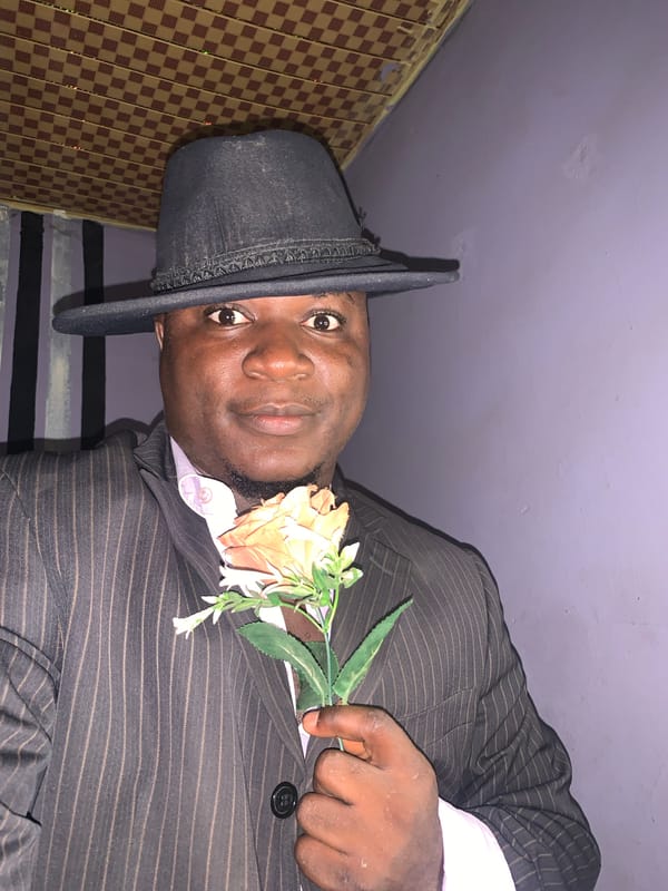 Man in decorated fedora photographed smoking in Akwanga