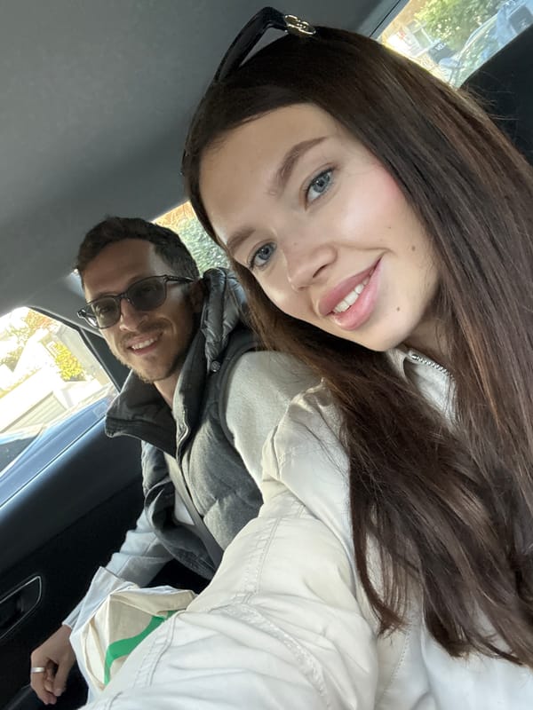 Two people pose for car photo in Glifada