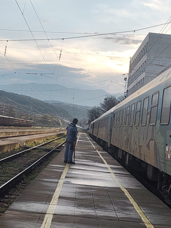 Man with cane waits on wet train platform in Mezdra