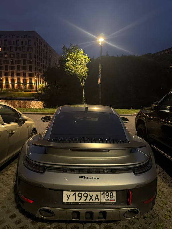 Luxury cars and a lit bridge in a waterfront city at night