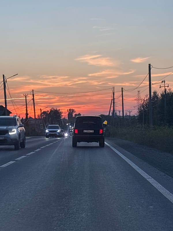 Sunset drive through Kazan traffic, sky glowing orange and pink.