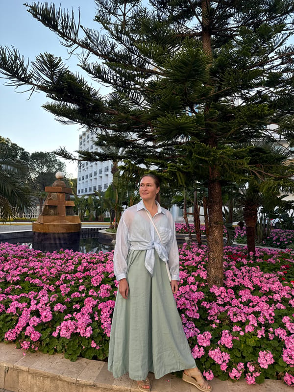 Woman poses by pink geraniums in Serik garden
