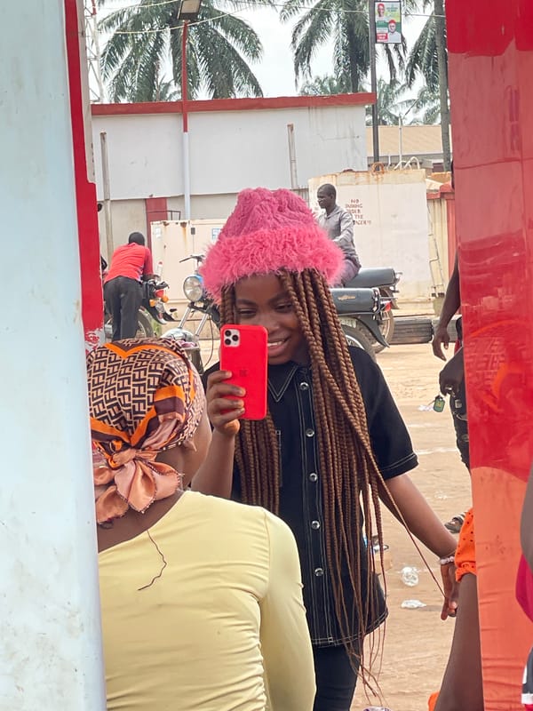 Woman with pink hat photographs herself in Amansee, Nigeria