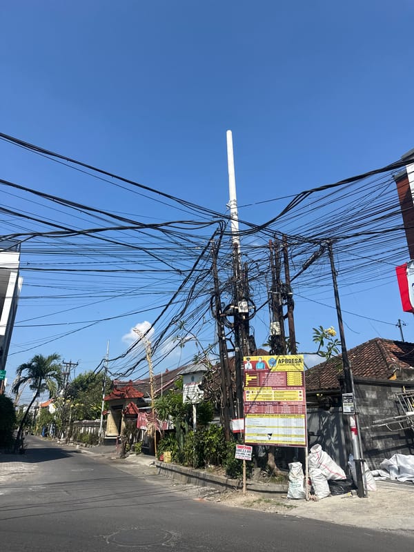 Denpasar street life: penjors, power lines, and passing traffic