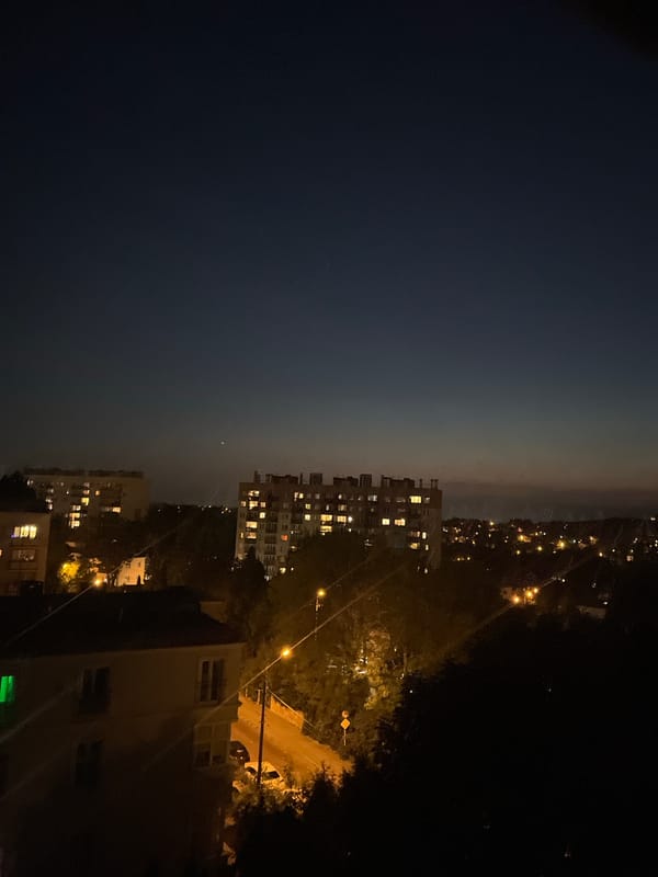 City skyline at dusk, shot from above as lights come on