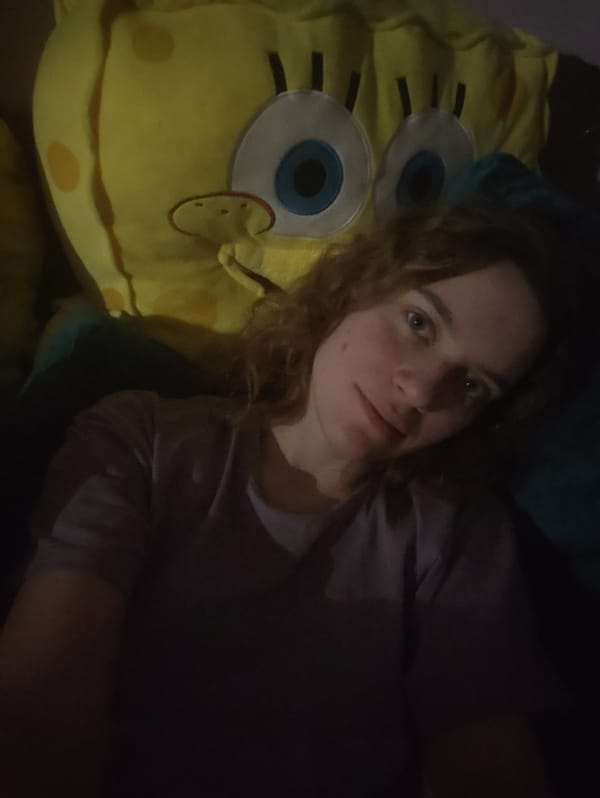 Person poses with large SpongeBob plush toy
