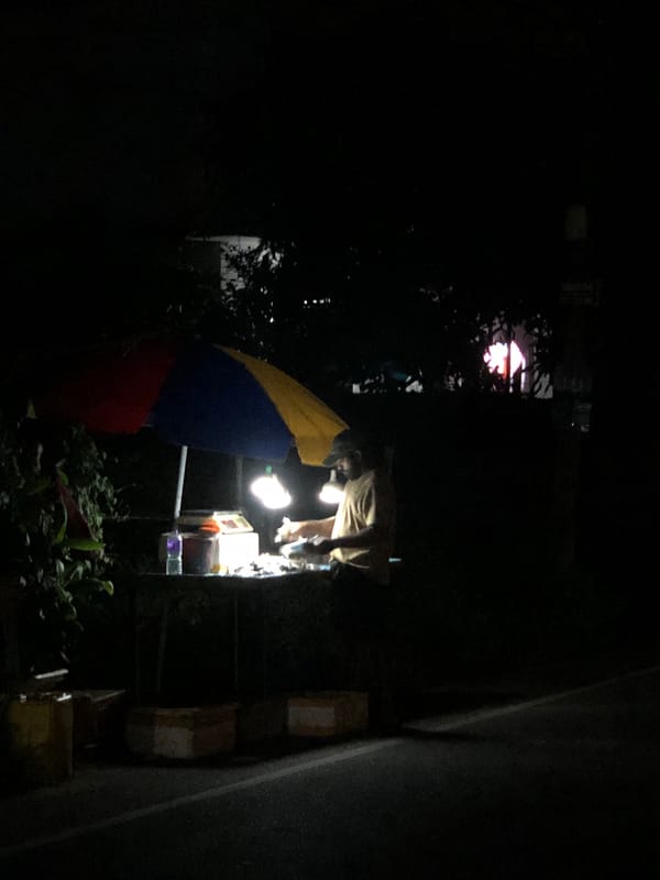 Nighttime food vendor operates illuminated roadside stall