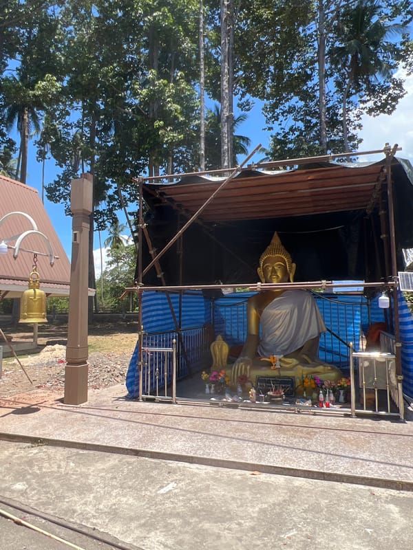 Buddha statue sheltered by temporary scaffolding structure in Thailand