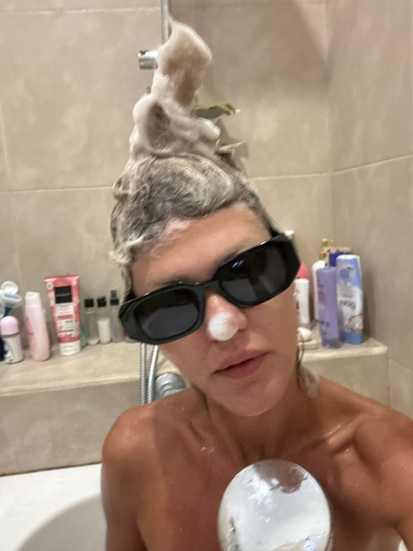 Person showers wearing sunglasses in North Kuta bathroom