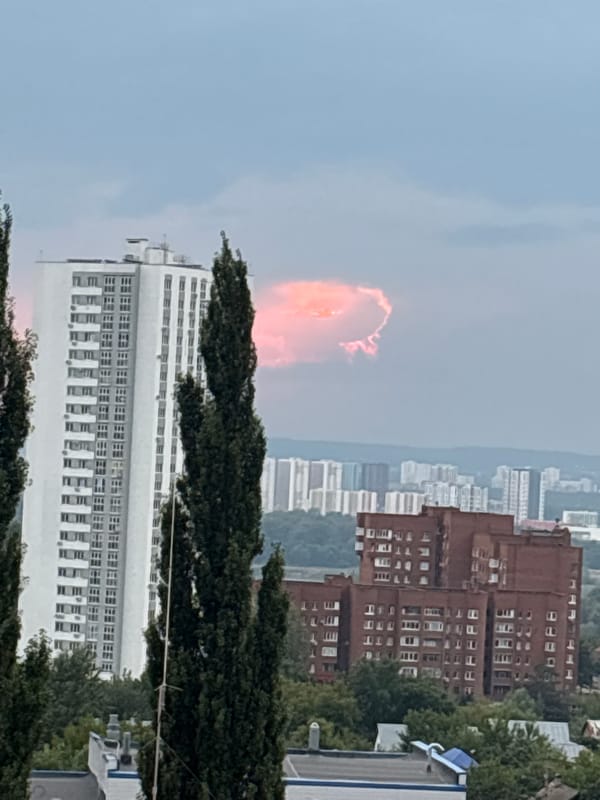 Ufa skyline with striking pink-orange clouds over city trees