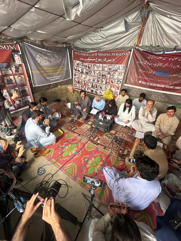 Indoor gathering on patterned rugs beneath framed photographs