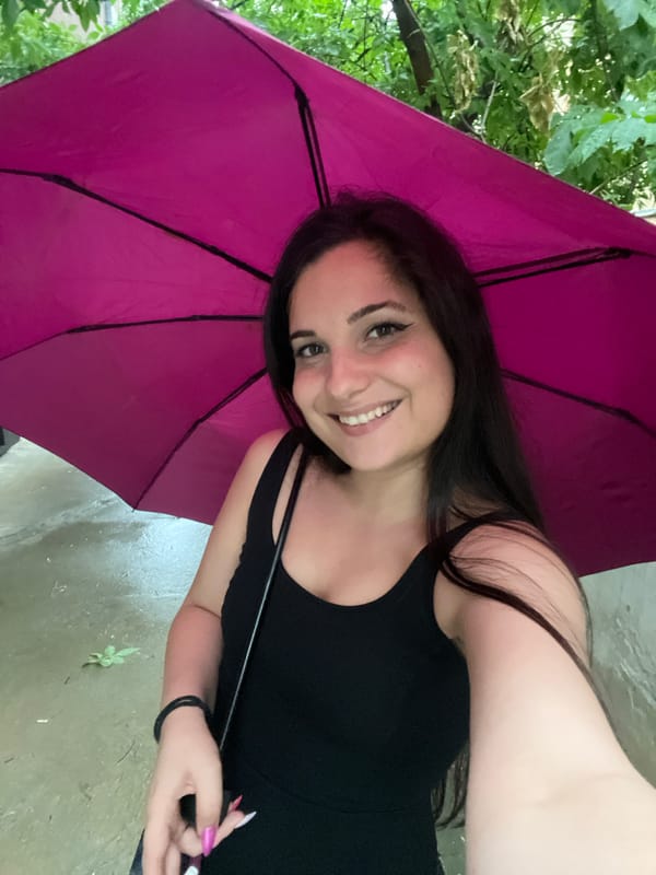 Jumping and laughing with a magenta umbrella on wet Sofia streets