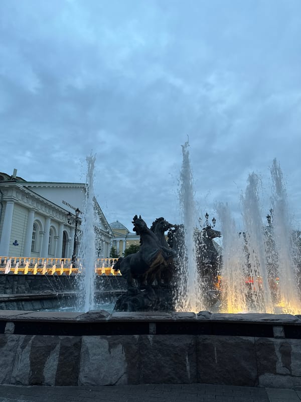 Tourists photograph Moscow's Manege Square fountain during evening visit