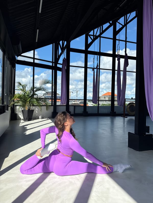Woman practices aerial yoga in lavender attire at Canggu studio