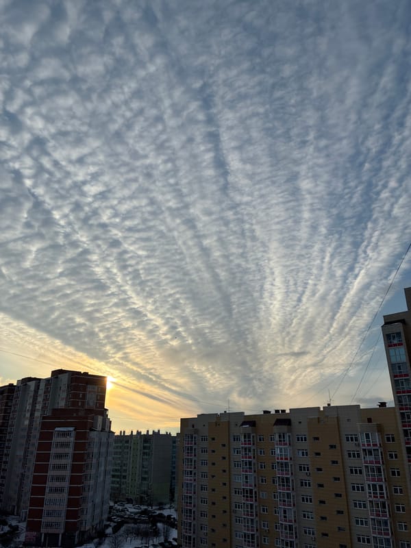 Urban skyview between apartment buildings shows striated clouds overhead