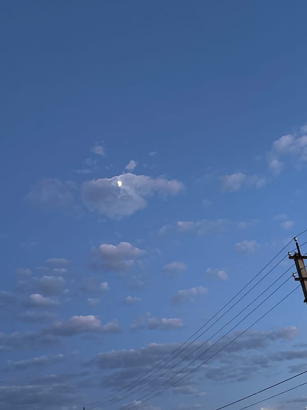 Day-to-dusk sky transition with crescent moon observed over urban area