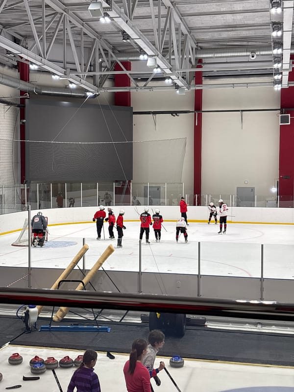 Hockey team practices in red jerseys at indoor arena