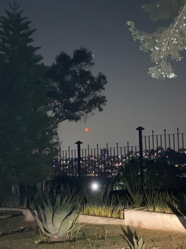 Red celestial object observed through clouds in Mexican suburb
