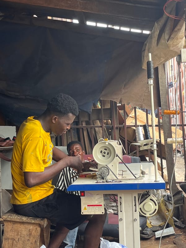 Two men work at sewing machine in Accra workspace