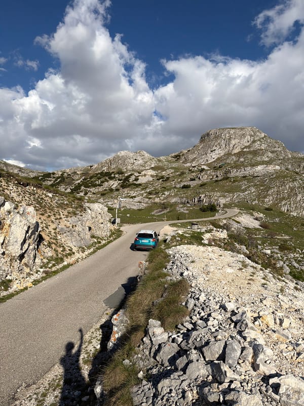 Turquoise car travels winding mountain road in Boričje, Montenegro