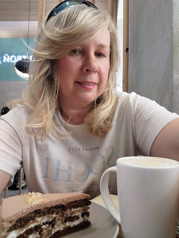 Woman enjoys cake and coffee at cafe