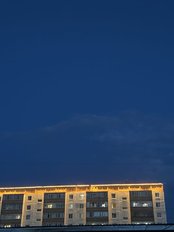 Roofline lights on a Kostanay apartment building at dusk