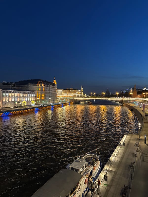 Evening cityscape observed along Moscow River featuring illuminated Stalinist architecture