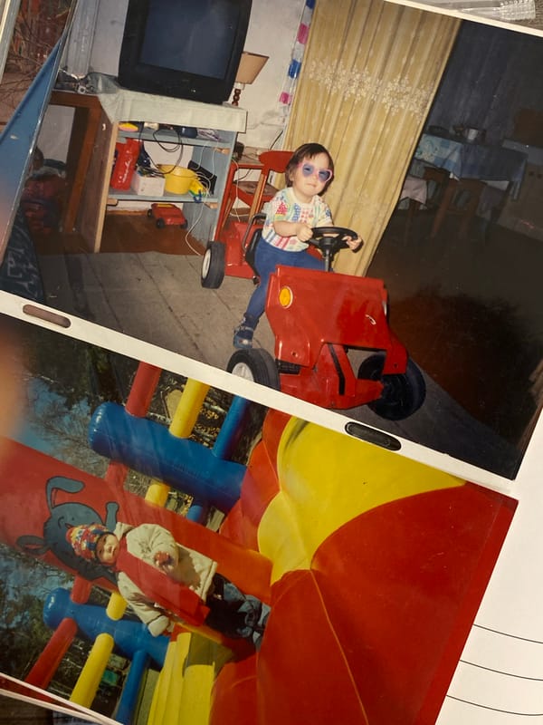 Child in heart sunglasses plays on toy tractor