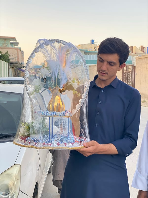 Man carries ornate gift basket on Kandahar street