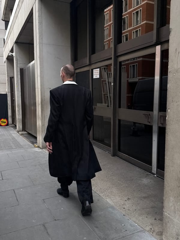 Man in black suit walks past London building