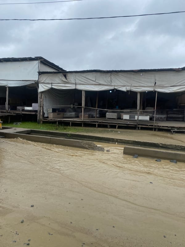 Muddy Nigerian market street on a wet, overcast day