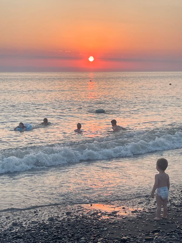 Calm beach sunset with people in the water