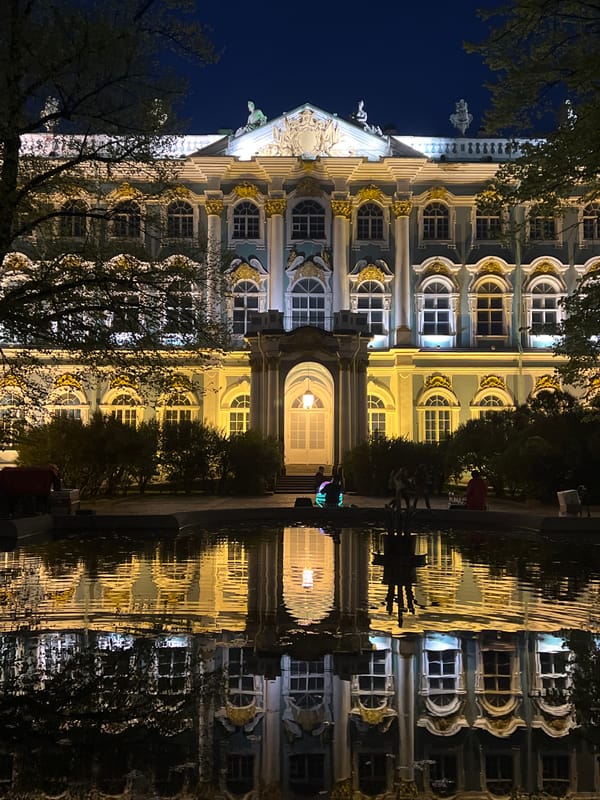 Night scenes around Winter Palace feature pedestrians, performer, Victory flags