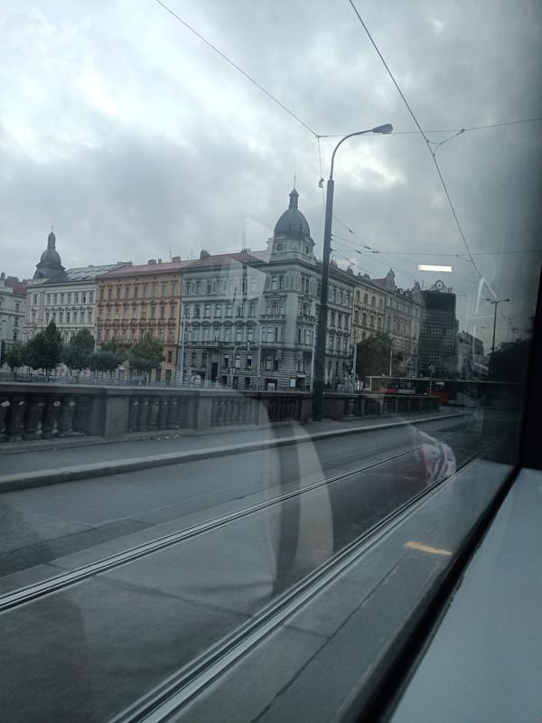 Trams and traffic moving through a cloudy Prague morning