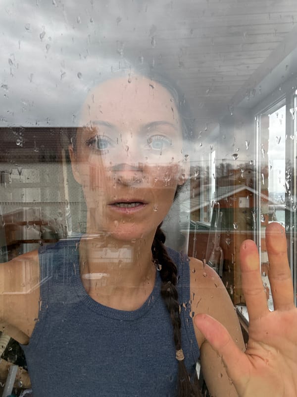Woman observed through rain-streaked window in Ulyanovsk morning