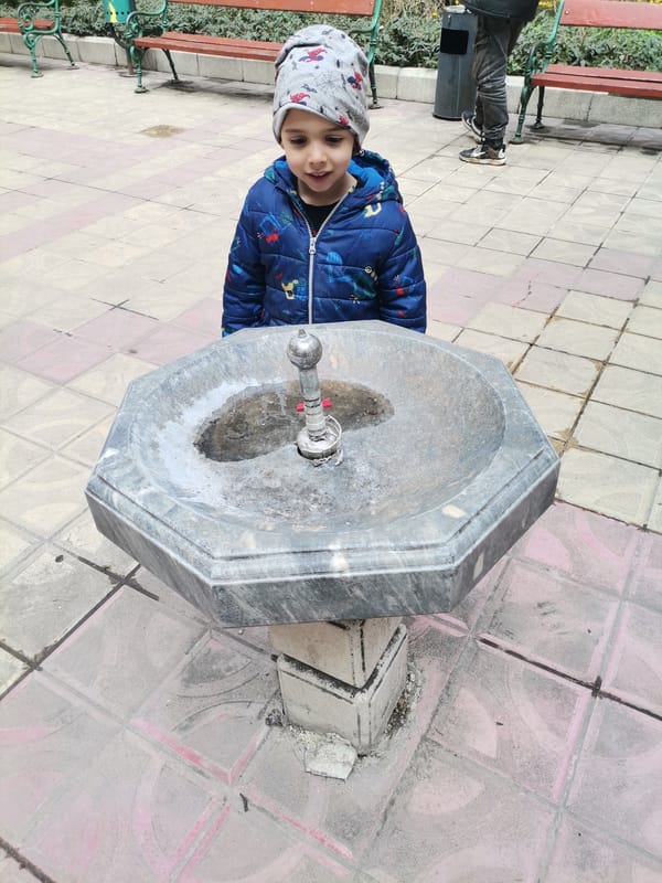 Child at public drinking fountain in Dobrich Bulgaria
