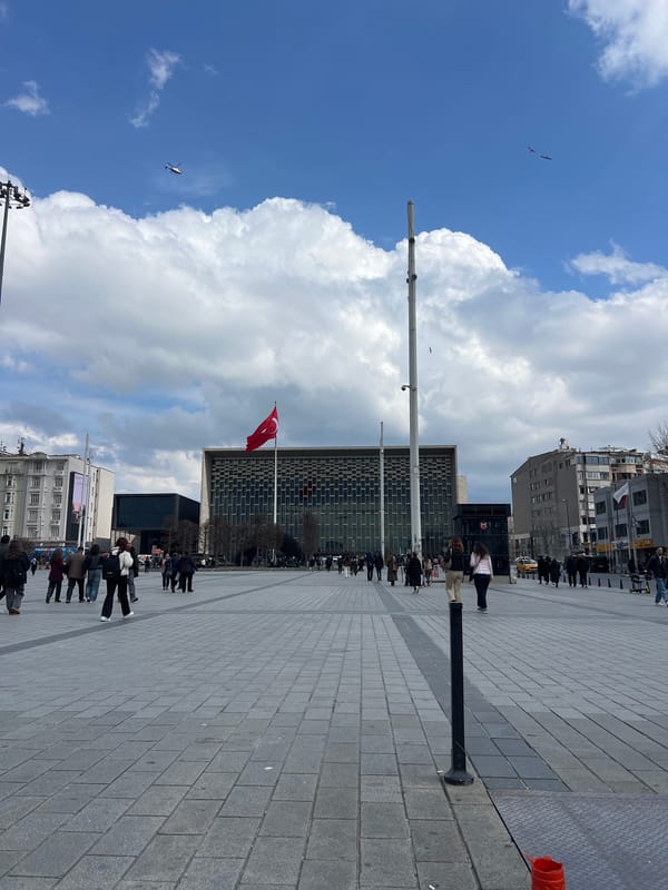 Pedestrians gather in Beyoğlu plaza near Turkish flag display